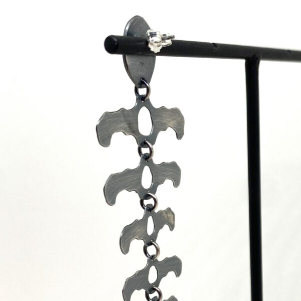 Longue boucle d'oreille en argent noirci.