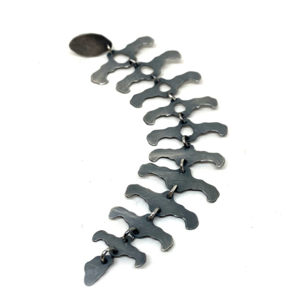 Longue boucle d'oreille en argent noirci.