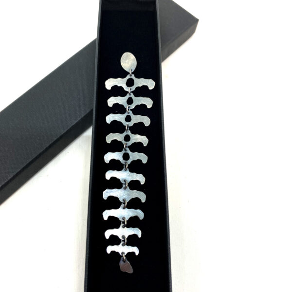 Longue boucle d'oreille en argent noirci.